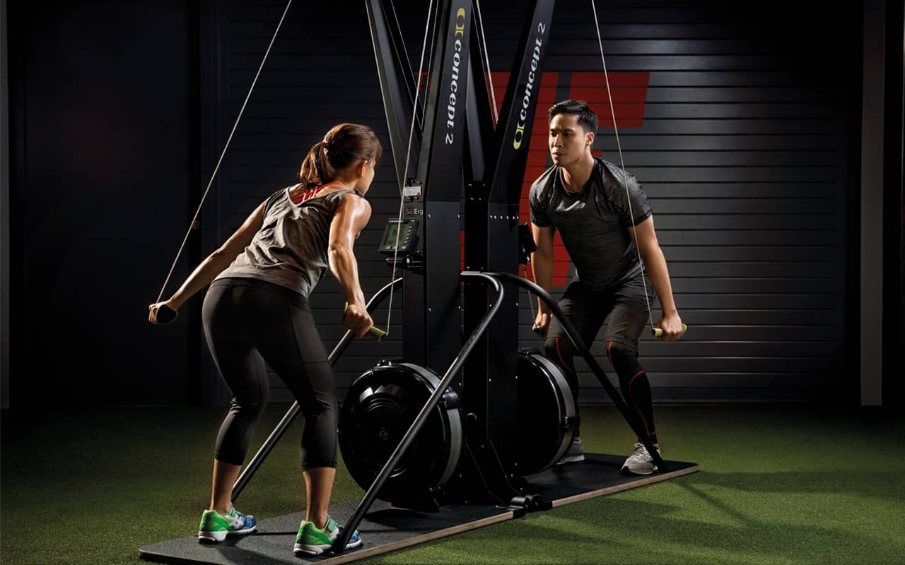 Two people working out with the SkiErg equipment.